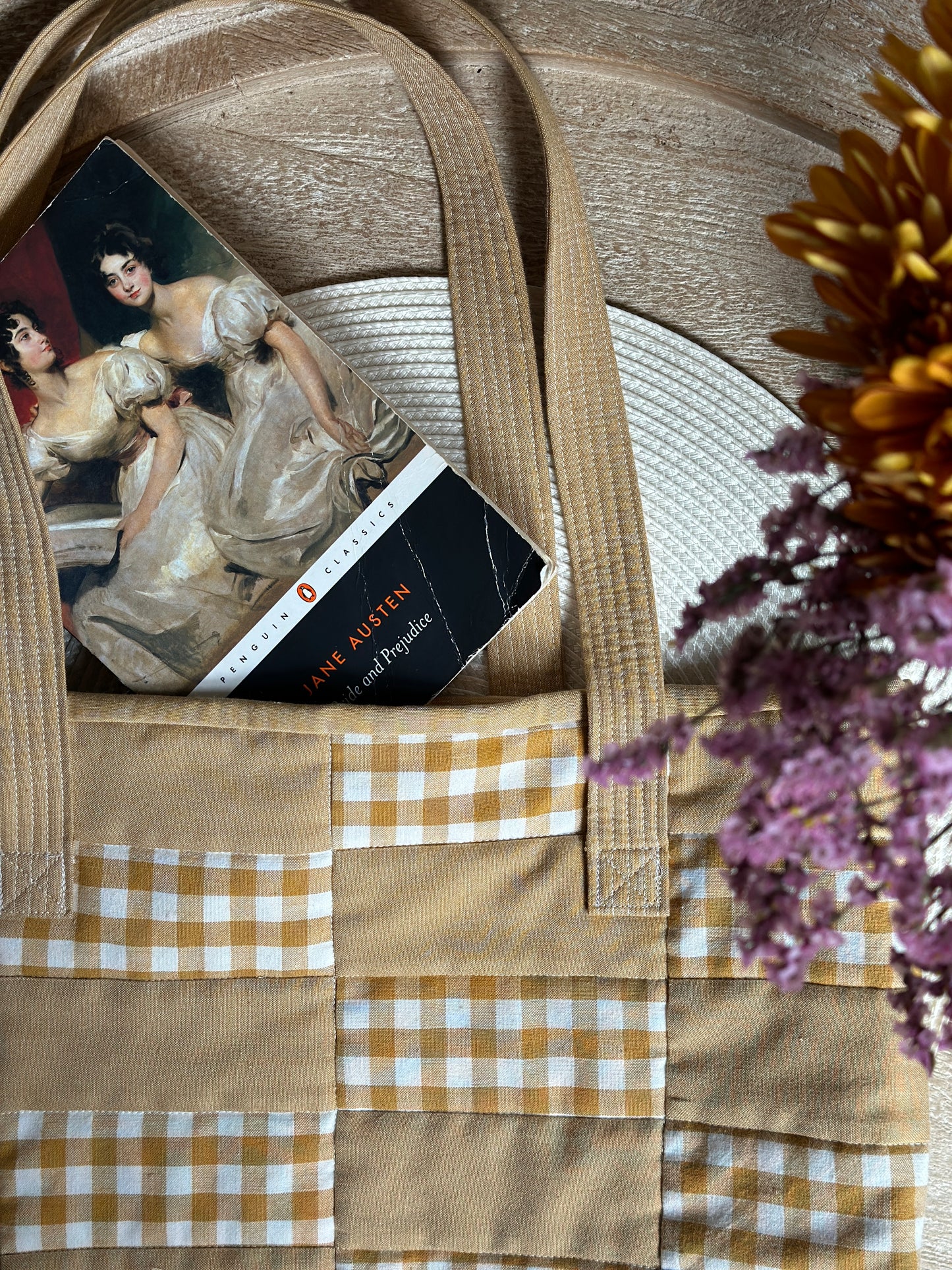 Close up of the super soft Due Pinoli Baseline Tote Bag made with Fableism Supply Co fabric and with the Jane Austen book Pride and Prejudice tucked inside and flowers peeking into the photo frame